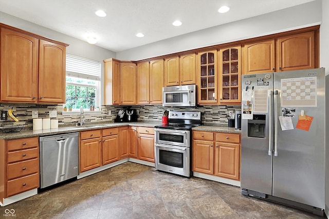 7312 Drum Castle Ct, Indianapolis, IN 46259 - kitchen featuring appliances with stainless steel finishes, a sink, decorative backsplash, glass insert cabinets, and recessed lighting