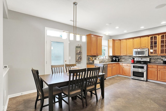 7312 Drum Castle Ct, Indianapolis, IN 46259 - kitchen with appliances with stainless steel finishes, decorative backsplash, a sink, glass insert cabinets, and recessed lighting