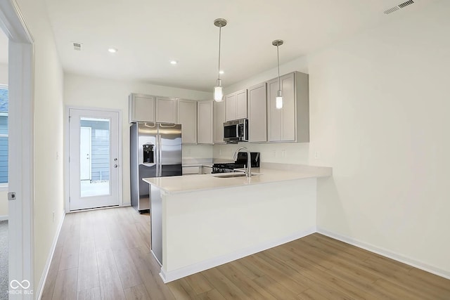 3927 Wren Dr, Brownsburg, IN 46112 - kitchen featuring stainless steel appliances, gray cabinetry, light wood finished floors, a peninsula, and light countertops