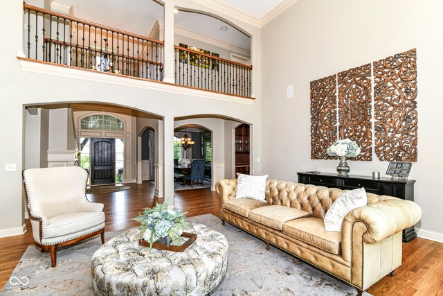 13909 Waterway Blvd, Fishers, IN 46040 - living room with arched walkways, wood finished floors, crown molding, baseboards, and a chandelier