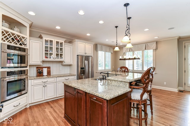 13909 Waterway Blvd, Fishers, IN 46040 - kitchen featuring appliances with stainless steel finishes, a kitchen breakfast bar, light wood-type flooring, crown molding, and white cabinetry