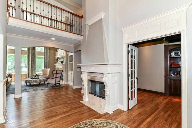 13909 Waterway Blvd, Fishers, IN 46040 - living area featuring a tiled fireplace, a towering ceiling, wood finished floors, arched walkways, and ornamental molding