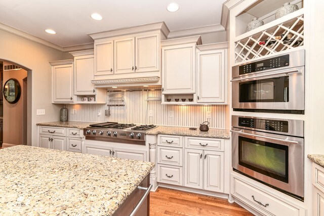 13909 Waterway Blvd, Fishers, IN 46040 - kitchen featuring appliances with stainless steel finishes, arched walkways, ornamental molding, light wood-style flooring, and light stone countertops