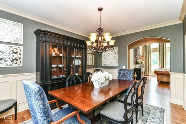 13909 Waterway Blvd, Fishers, IN 46040 - dining area with arched walkways, a chandelier, light wood-type flooring, crown molding, and wainscoting