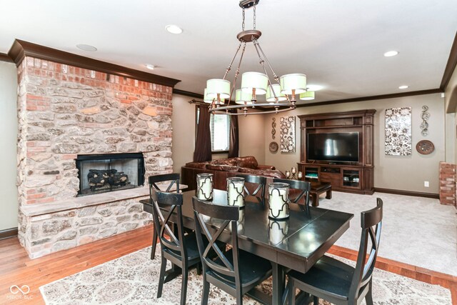 13909 Waterway Blvd, Fishers, IN 46040 - dining space featuring ornamental molding, baseboards, a chandelier, a stone fireplace, and wood finished floors