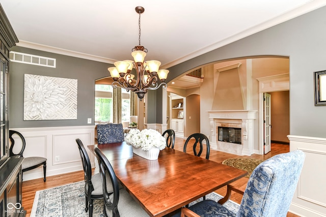 13909 Waterway Blvd, Fishers, IN 46040 - dining room featuring arched walkways, a chandelier, wood finished floors, crown molding, and a fireplace