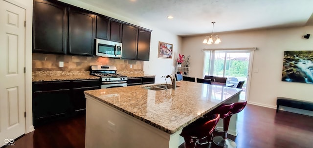 6110 Pelican Ln, Columbus, IN 47201 - kitchen featuring appliances with stainless steel finishes, a sink, dark wood-style flooring, tasteful backsplash, and light stone countertops