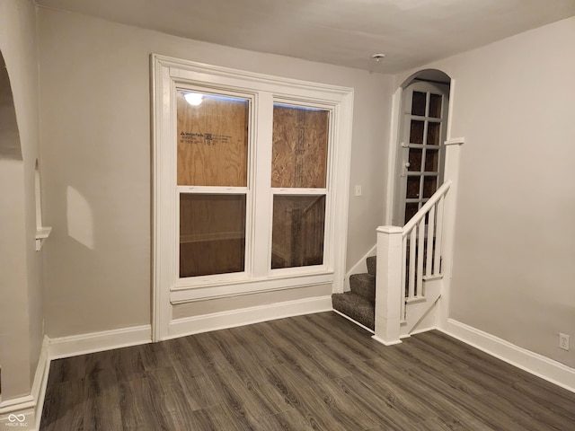 323-325 N Gladstone Ave, Indianapolis, IN 46201 - empty room featuring dark wood-type flooring, baseboards, arched walkways, and stairway