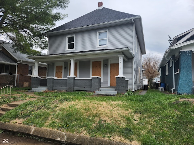 323-325 N Gladstone Ave, Indianapolis, IN 46201 - american foursquare style home with a porch, a front lawn, a chimney, central AC unit, and brick siding