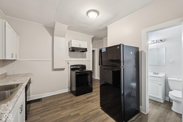 323-325 N Gladstone Ave, Indianapolis, IN 46201 - kitchen with black appliances, under cabinet range hood, white cabinets, dark wood-style floors, and baseboards