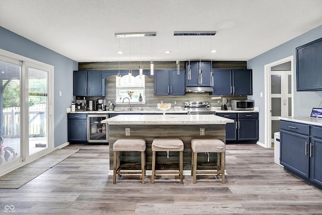 9001 Harrison Run Ct, Indianapolis, IN 46256 - kitchen featuring stainless steel appliances, under cabinet range hood, wine cooler, a breakfast bar, and a sink