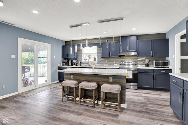 9001 Harrison Run Ct, Indianapolis, IN 46256 - kitchen with stainless steel appliances, a textured ceiling, a kitchen breakfast bar, under cabinet range hood, and a center island