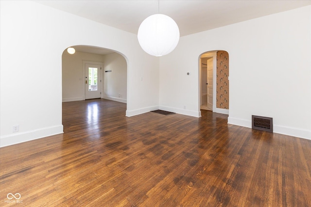 1311 N Oakland Ave, Indianapolis, IN 46201 - unfurnished room with arched walkways, dark wood-style floors, and baseboards