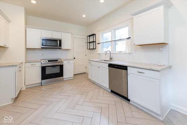 1311 N Oakland Ave, Indianapolis, IN 46201 - kitchen with appliances with stainless steel finishes, a sink, recessed lighting, backsplash, and white cabinetry
