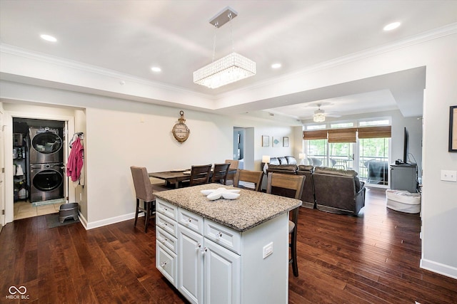 20971 Shoreline Ct Unit 201, Noblesville, IN 46062 - kitchen with estacked washer and dryer, a raised ceiling, a breakfast bar, dark wood-style floors, and ornamental molding