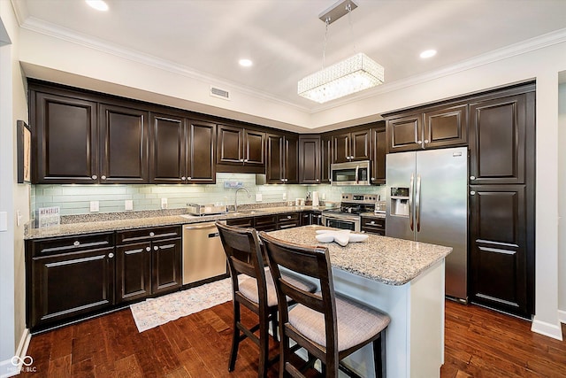 20971 Shoreline Ct Unit 201, Noblesville, IN 46062 - kitchen featuring stainless steel appliances, crown molding, light stone counters, a kitchen breakfast bar, and dark wood-style flooring