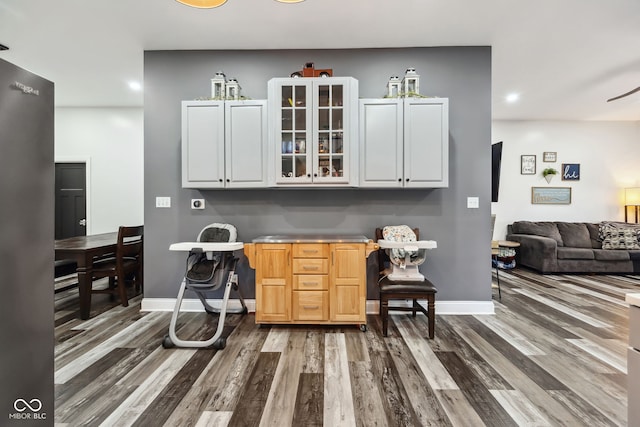 117 N Market St, Thorntown, IN 46071 - kitchen featuring dark wood-style flooring, recessed lighting, baseboards, glass insert cabinets, and white cabinetry