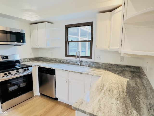 5130 Navajo Ct, Columbus, IN 47203 - kitchen with appliances with stainless steel finishes, a sink, light stone counters, white cabinetry, and light wood-type flooring