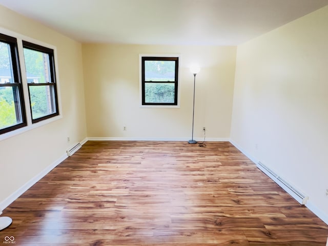 5130 Navajo Ct, Columbus, IN 47203 - empty room featuring a baseboard heating unit, healthy amount of natural light, wood finished floors, and baseboards