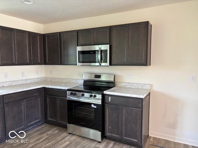 3805 Windstar Way, Columbus, IN 47203 - kitchen with appliances with stainless steel finishes, light wood finished floors, light countertops, dark brown cabinets, and baseboards