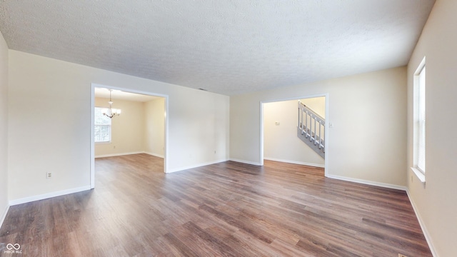 3916 Jekyll Ct, Indianapolis, IN 46237 - empty room featuring a chandelier, wood finished floors, a textured ceiling, baseboards, and stairway