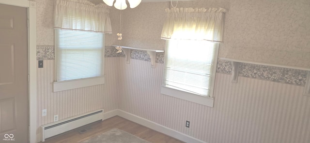 3107 N 100 W, Shelbyville, IN 46176 - unfurnished dining area with a baseboard radiator, wood finished floors, wallpapered walls, ceiling fan, and a wainscoted wall