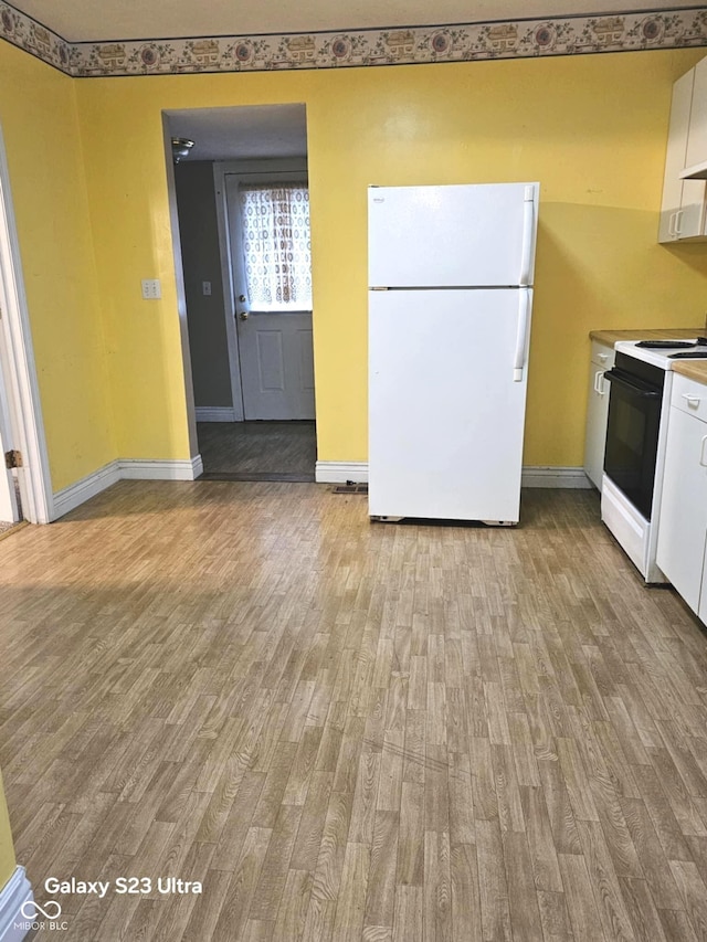 208 E Madison St E, Alexandria, IN 46001 - kitchen featuring freestanding refrigerator, electric stove, light wood-type flooring, baseboards, and white cabinetry