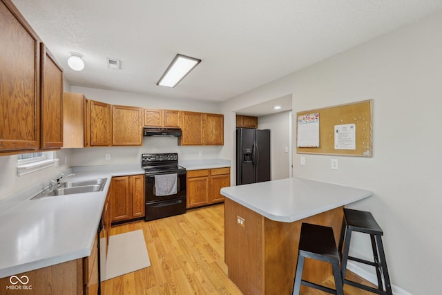 764 Port Dr, Avon, IN 46123 - kitchen featuring black appliances, a peninsula, light wood finished floors, a kitchen breakfast bar, and brown cabinets