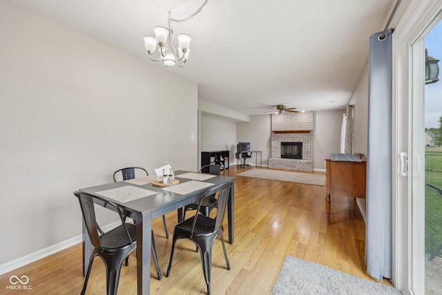 764 Port Dr, Avon, IN 46123 - dining area with a fireplace, a chandelier, light wood-style flooring, and baseboards