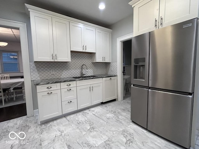 4040 Carrollton Ave, Indianapolis, IN 46205 - kitchen featuring stainless steel fridge with ice dispenser, a sink, decorative backsplash, dark stone counters, and light marble finish flooring