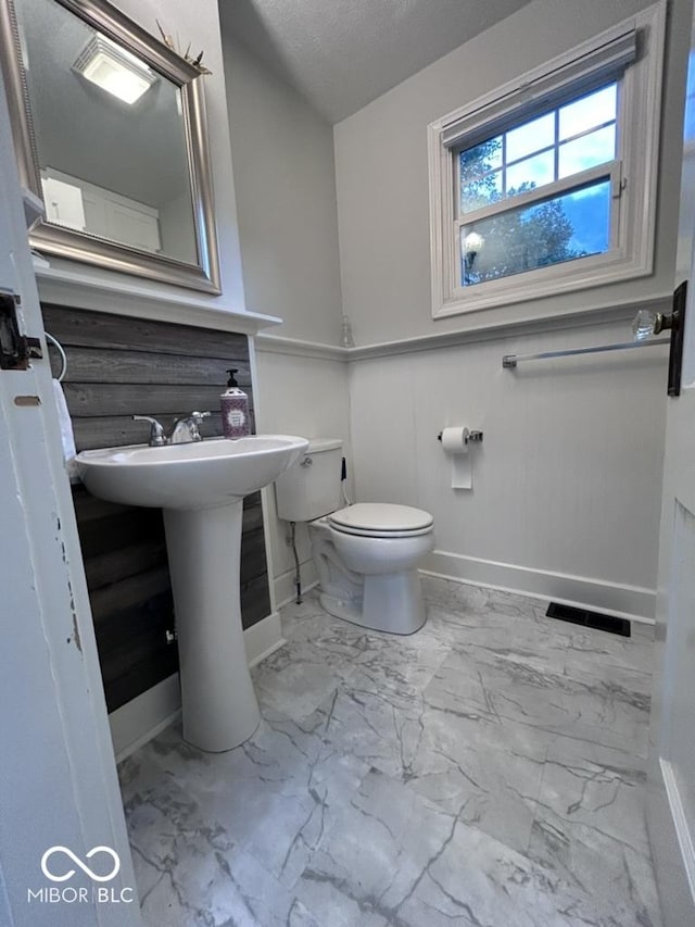 4040 Carrollton Ave, Indianapolis, IN 46205 - half bath featuring baseboards, marble finish floors, toilet, and a sink