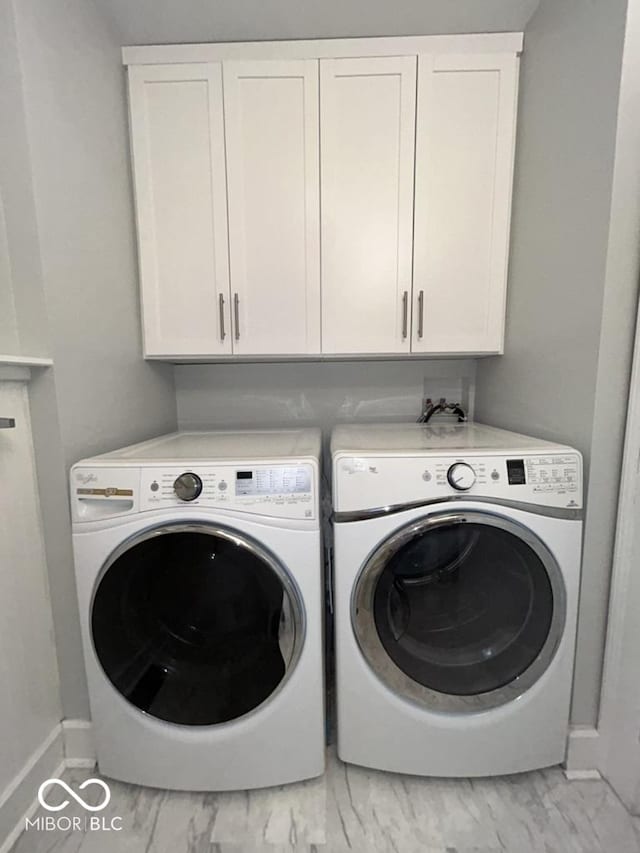 4040 Carrollton Ave, Indianapolis, IN 46205 - washroom with washing machine and clothes dryer, baseboards, light marble finish floors, and cabinet space