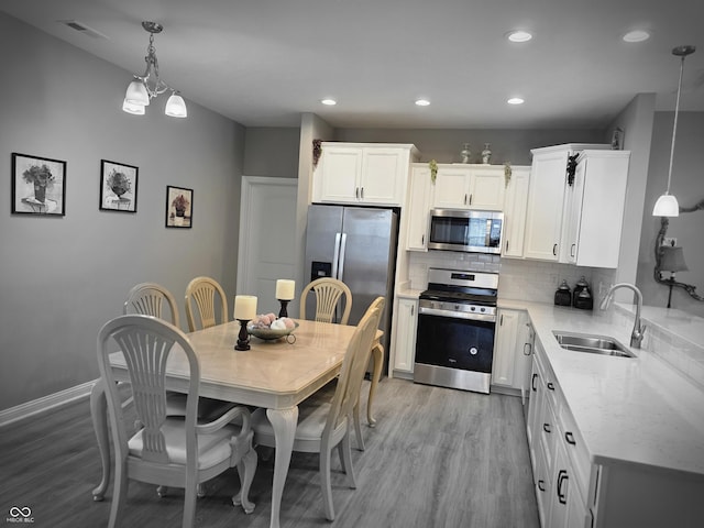 9106 Hedley Way E, Avon, IN 46123 - kitchen with appliances with stainless steel finishes, a sink, light wood-style flooring, tasteful backsplash, and recessed lighting