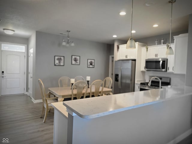 9106 Hedley Way E, Avon, IN 46123 - kitchen featuring appliances with stainless steel finishes, dark wood finished floors, decorative light fixtures, a peninsula, and recessed lighting