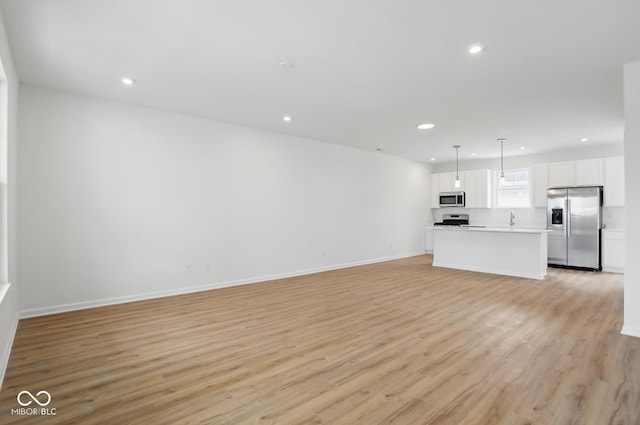 3947 Wren Dr, Brownsburg, IN 46112 - unfurnished living room with light wood-style flooring, recessed lighting, baseboards, and a sink