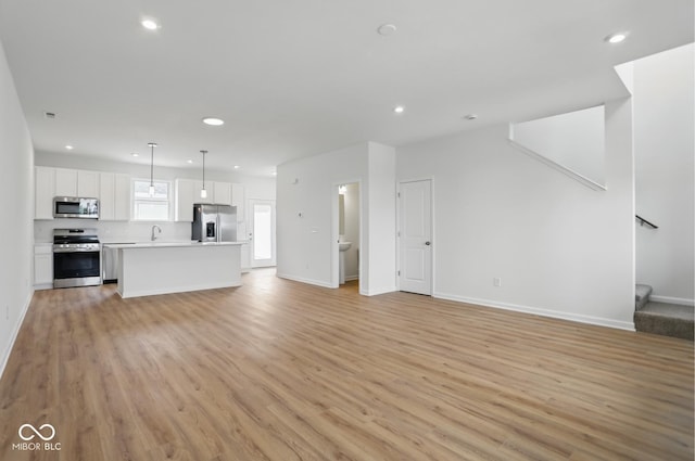 3947 Wren Dr, Brownsburg, IN 46112 - unfurnished living room featuring recessed lighting, light wood-type flooring, a sink, stairs, and baseboards