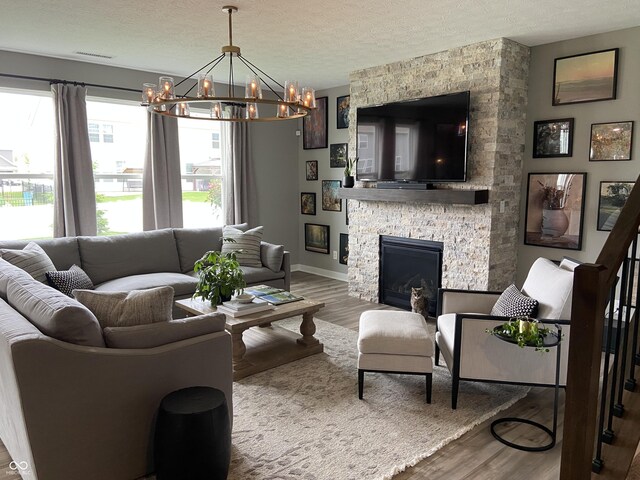 8876 Boylan Pl, Pendleton, IN 46064 - living room with a chandelier, wood finished floors, a textured ceiling, a fireplace, and baseboards