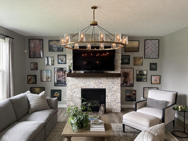 8876 Boylan Pl, Pendleton, IN 46064 - living area featuring a chandelier, wood finished floors, baseboards, a textured ceiling, and a fireplace