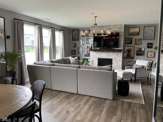 8876 Boylan Pl, Pendleton, IN 46064 - living area with wood finished floors, a chandelier, a stone fireplace, and a textured ceiling