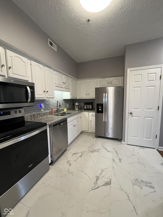 7601 Newport Bay Dr Unit 203, Indianapolis, IN 46240 - kitchen with appliances with stainless steel finishes, a sink, light marble finish floors, stone counters, and white cabinets