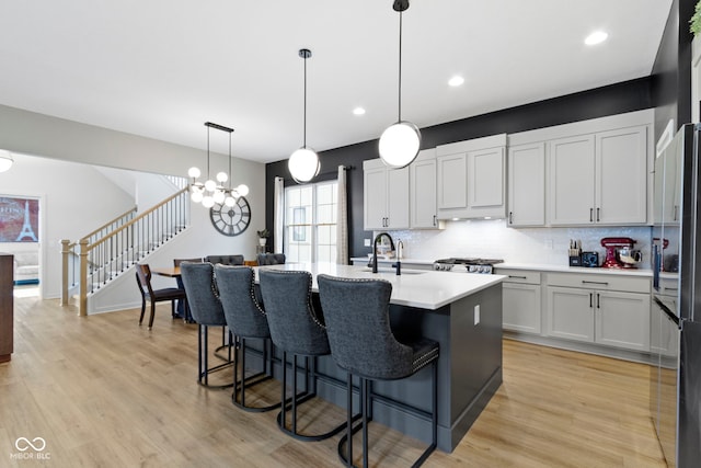 17359 Wilkes Way, Westfield, IN 46074 - kitchen with a sink, tasteful backsplash, light countertops, a breakfast bar, and a chandelier