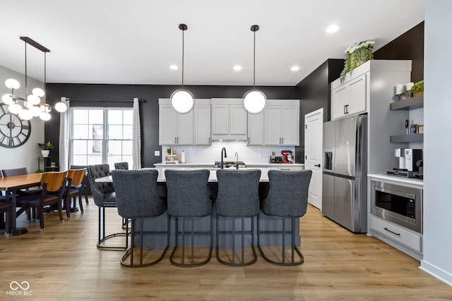 17359 Wilkes Way, Westfield, IN 46074 - kitchen with appliances with stainless steel finishes, light countertops, a kitchen breakfast bar, a center island with sink, and backsplash