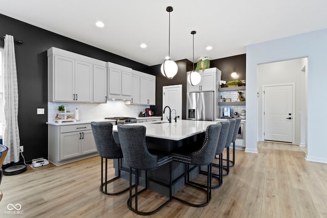 17359 Wilkes Way, Westfield, IN 46074 - kitchen with stainless steel fridge with ice dispenser, backsplash, light countertops, light wood-style flooring, and a kitchen breakfast bar