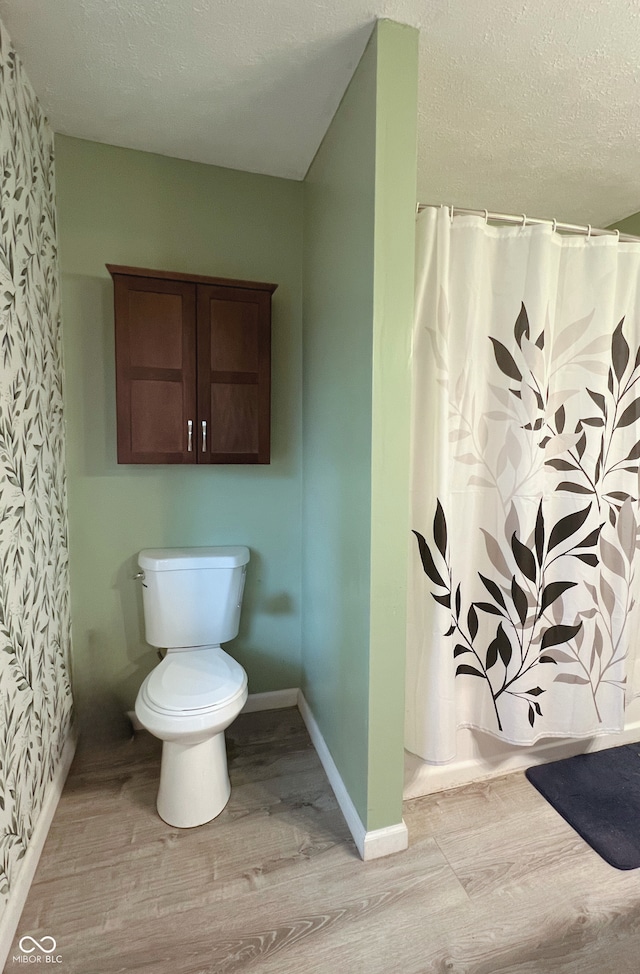 6460 W US Highway 50, North Vernon, IN 47265 - bathroom with wood finished floors, toilet, wallpapered walls, a textured ceiling, and baseboards