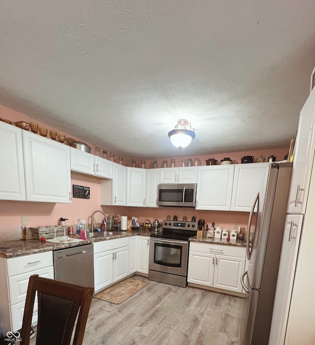 6460 W US Highway 50, North Vernon, IN 47265 - kitchen with appliances with stainless steel finishes, a sink, light wood-type flooring, white cabinetry, and a textured ceiling