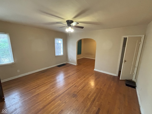 5472 E 10th St, Indianapolis, IN 46219 - spare room with arched walkways, ceiling fan, wood finished floors, and baseboards