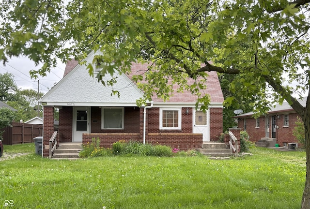 5472 E 10th St, Indianapolis, IN 46219 - view of front of home featuring brick siding, a chimney, a porch, central air condition unit, and a shingled roof