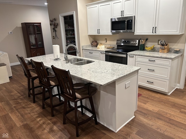 308 Bay Ridge Dr, Pendleton, IN 46064 - kitchen featuring appliances with stainless steel finishes, a sink, dark wood-type flooring, a kitchen island with sink, and white cabinets