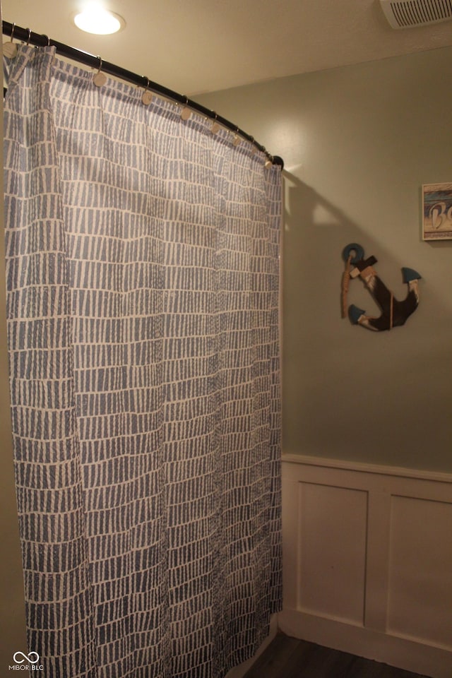5101 W Bay Rd, Plainfield, IN 46168 - bathroom featuring a wainscoted wall, wood finished floors, curtained shower, and a decorative wall