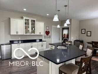 217 N Liberty Blvd, Mooresville, IN 46158 - kitchen featuring a sink, dark countertops, a kitchen island with sink, white cabinets, and dark wood-style floors